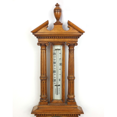 1145 - Oak aneroid barometer thermometer, with broken arch pediment and urn finial, 95cm in length