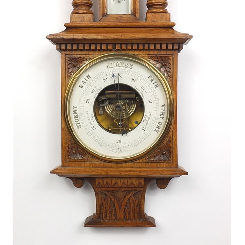 1145 - Oak aneroid barometer thermometer, with broken arch pediment and urn finial, 95cm in length