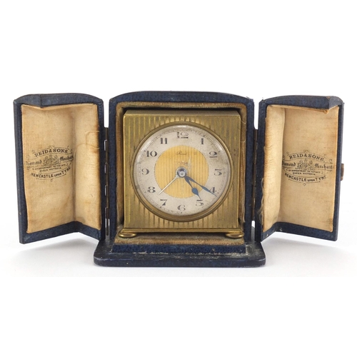 1135 - Art Deco brass travel alarm clock retailed by Reid  & Sons, with fitted case, 5.8cm high