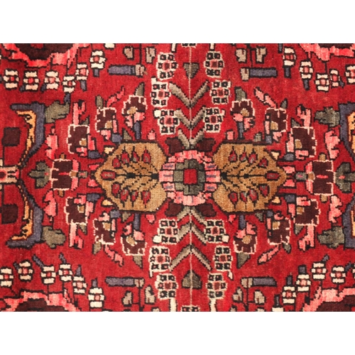 2050 - Rectangular Persian Shiraz carpet runner, having all over floral motifs onto a dark red ground, 277c... 