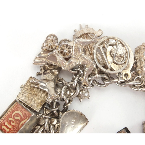 2567 - Heavy silver charm bracelet with a large selection of mostly silver charms including, emergency note... 