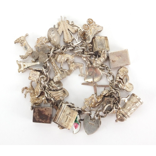 2567 - Heavy silver charm bracelet with a large selection of mostly silver charms including, emergency note... 