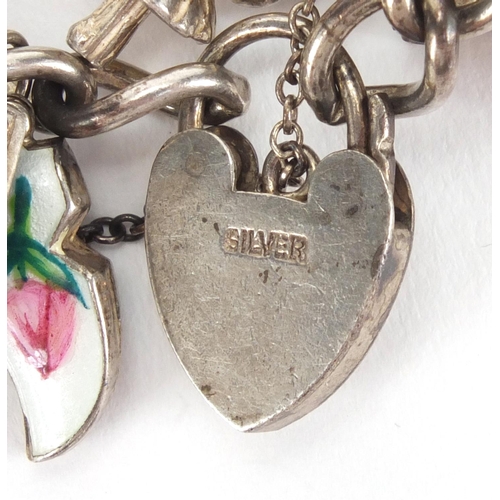 2567 - Heavy silver charm bracelet with a large selection of mostly silver charms including, emergency note... 