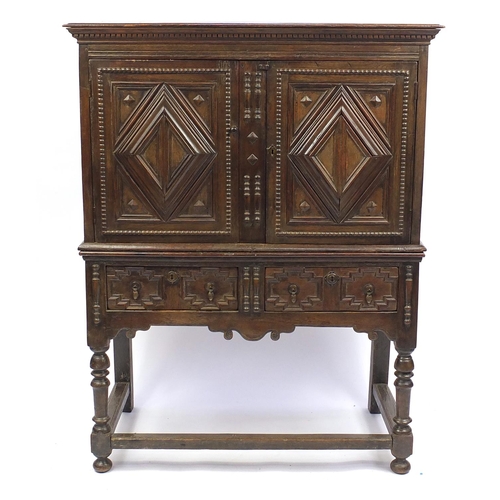 2044 - Jacobean style cabinet on stand fitted with a pair of lozenge relief doors above a pair of drawers o... 