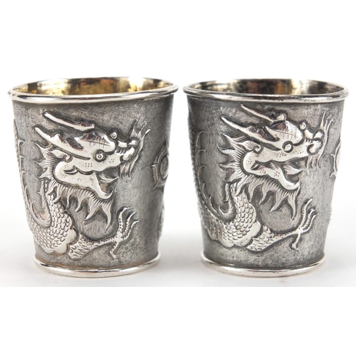 523 - Pair of Chinese silver beakers by Wang Hing, each embossed with a dragon chasing the flaming pearl a... 