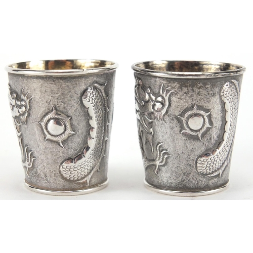 523 - Pair of Chinese silver beakers by Wang Hing, each embossed with a dragon chasing the flaming pearl a... 