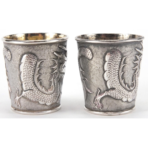 523 - Pair of Chinese silver beakers by Wang Hing, each embossed with a dragon chasing the flaming pearl a... 