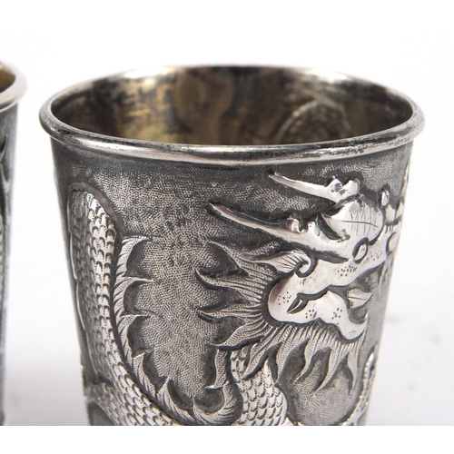 523 - Pair of Chinese silver beakers by Wang Hing, each embossed with a dragon chasing the flaming pearl a... 