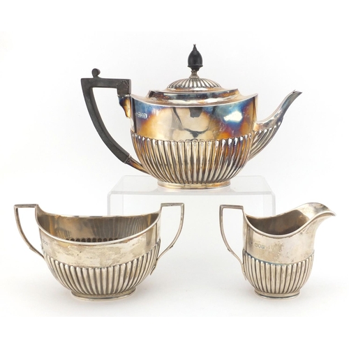 714 - Victorian silver three piece tea service with demi fluted decoration, the teapot with ebonised wood ... 