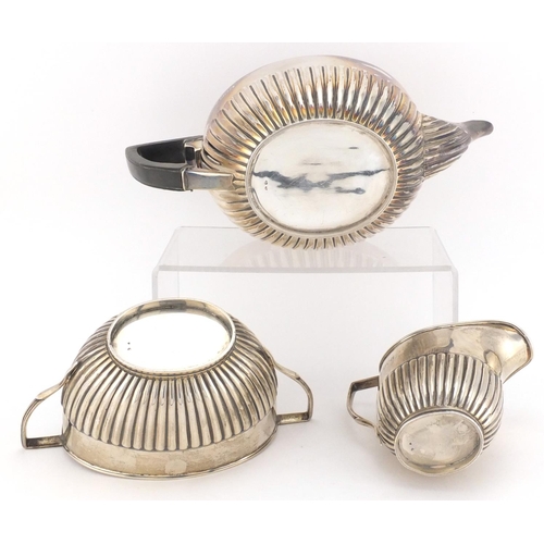 714 - Victorian silver three piece tea service with demi fluted decoration, the teapot with ebonised wood ... 