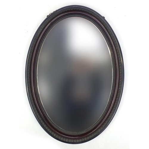 21 - Oval ebonised and mahogany framed bevelled edge mirror, 63cm x 86cm