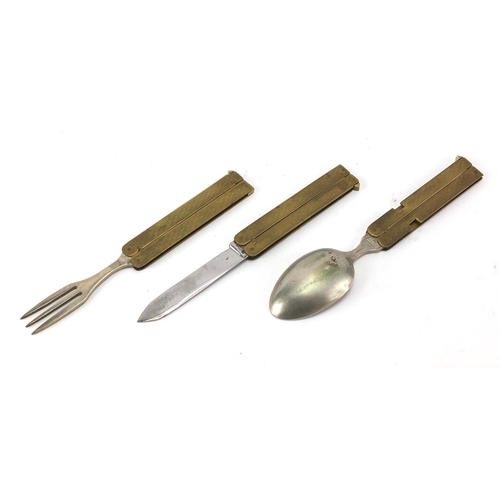 115 - Military interest brass and stainless steel folding campaign cutlery housed in a leather case, with ... 