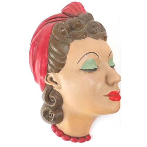 674 - Three hand painted Art Deco plaster wall masks, all of females, the largest 28cm high