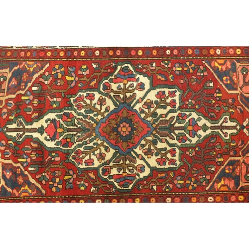2031 - Rectangular Persian rug having all over floral motifs with corresponding borders onto a predominantl... 