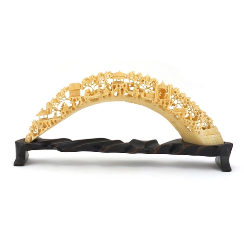 514 - Chinese ivory bridge on hardwood stand, profusely carved with workmen, trees and pagodas, 25cm wide