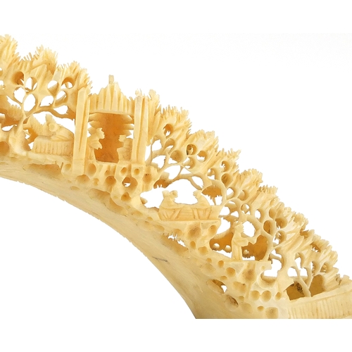 514 - Chinese ivory bridge on hardwood stand, profusely carved with workmen, trees and pagodas, 25cm wide