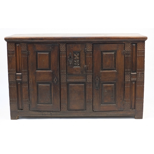 33 - Antique carved oak court cupboard fitted with three fielded panelled doors, 104cm H x 170cm W x 57cm... 