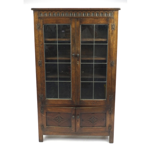 40 - Carved oak bookcase fitted with a pair of leaded glass doors above a pair of cupboard doors, 112cm H... 
