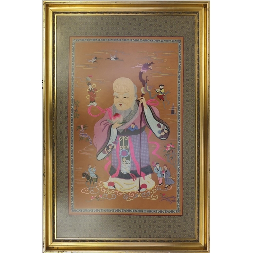 93 - Large Oriental silk tapestry of an elder holding a staff and fruit, gilt framed, 105cm x 64cm