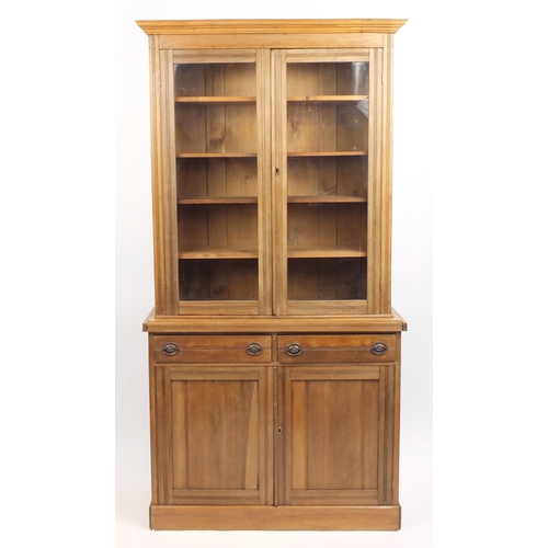 24 - Pine bookcase fitted with a pair of glazed doors, enclosing four adjustable shelves above a pair of ... 
