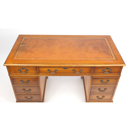 43 - Yew twin pedestal desk with tooled leather top, fitted with a series of drawers, 77cm H x 124cm W x ... 