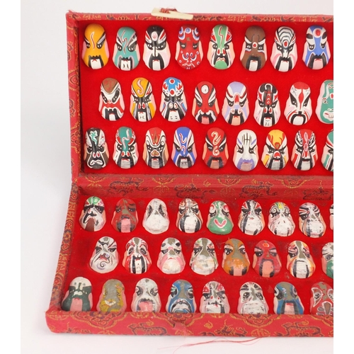 560 - Two sets of Chinese hand painted face masks housed in fitted cases, the largest 43cm wide