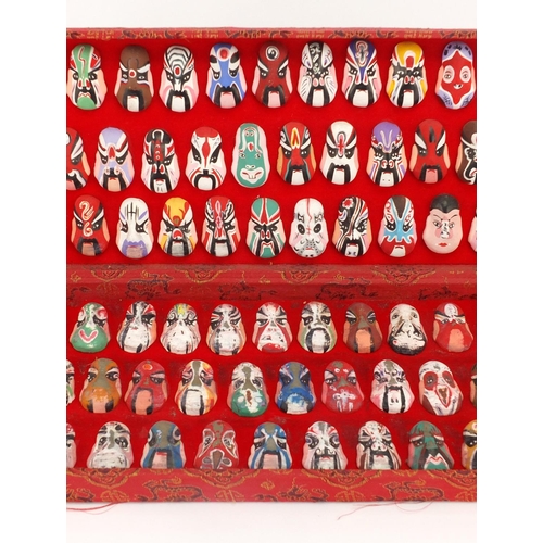 560 - Two sets of Chinese hand painted face masks housed in fitted cases, the largest 43cm wide