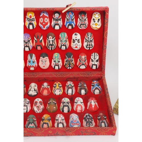 560 - Two sets of Chinese hand painted face masks housed in fitted cases, the largest 43cm wide