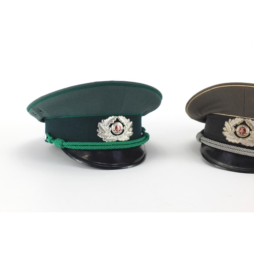 719 - Two  Russian Military interest style peaked caps with Insignia