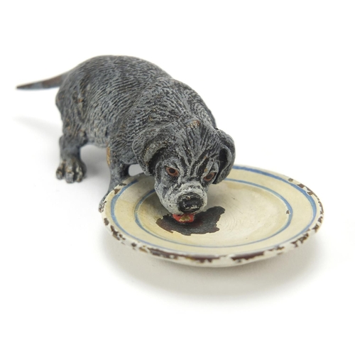 5 - Austrian cold painted bronze dog licking a plate, stamped Geschutzt to the base, 9cm in length