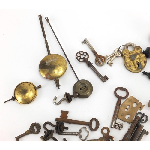 555 - Group of antique and later keys, locks and clock pendulums