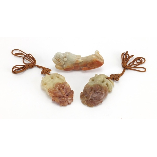 433 - Three Chinese russet and green jade pendants including a pair carved as mythical animals, with cords... 