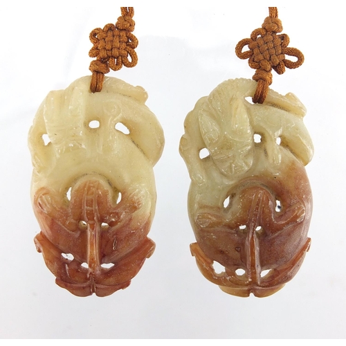 433 - Three Chinese russet and green jade pendants including a pair carved as mythical animals, with cords... 