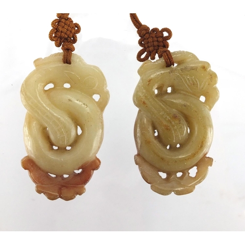 433 - Three Chinese russet and green jade pendants including a pair carved as mythical animals, with cords... 