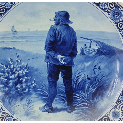 537 - Delft blue and white pottery charger, hand painted with a sailor smoking a pipe within a floral bord... 