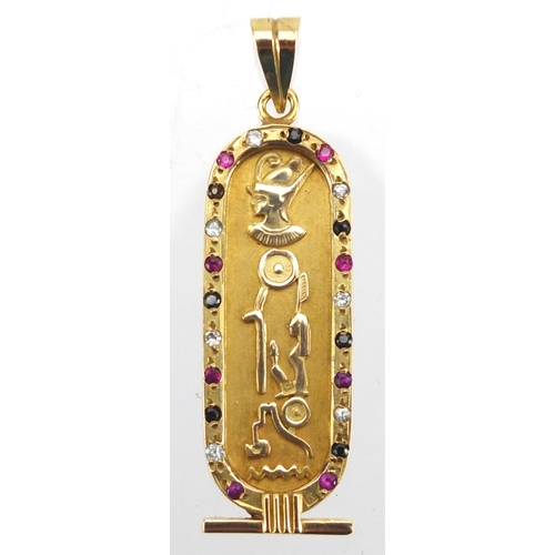 696 - Egyptian gold pendant decorated in relief with hieroglyphics and set with colourful stones, 5.5cm in... 