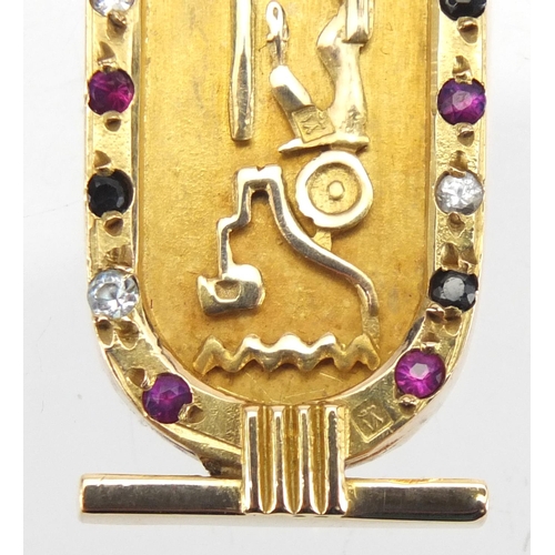 696 - Egyptian gold pendant decorated in relief with hieroglyphics and set with colourful stones, 5.5cm in... 