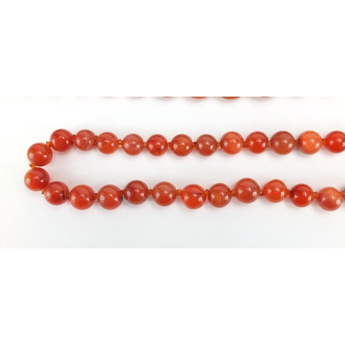 793 - Two amber coloured bead necklaces and a cornelian bead necklace, the largest 80cm in length, approxi... 