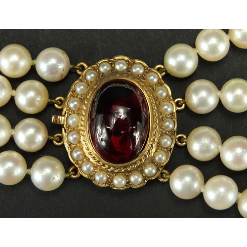 687 - Four row pearl necklace with 9ct gold cabochon garnet clasp, 40cm in length, approximate weight 115.... 