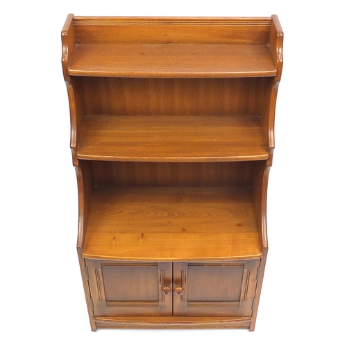 2052 - Ercol waterfall bookcase with cupboard door base, 111cm H x 61cm W x 33cm D