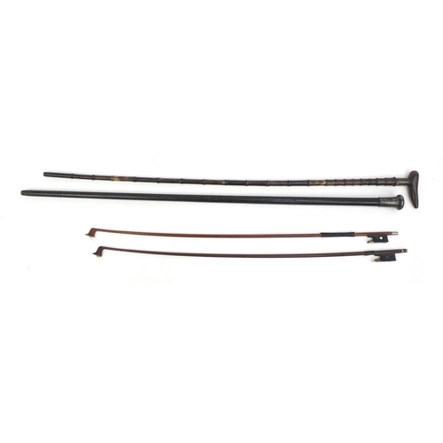 246 - Ebonised walking cane with silver handle, a horn walking cane and two violin bows