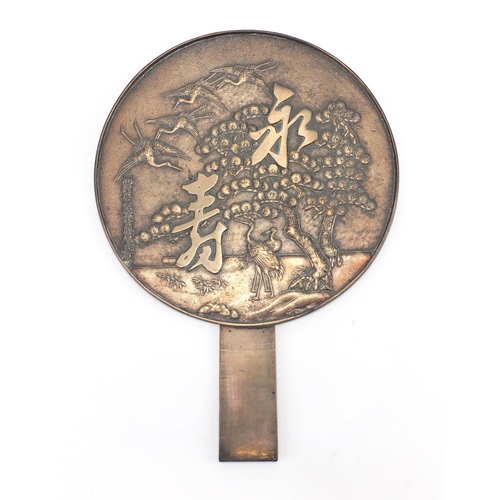 402 - Oriental polished bronze hand mirror cast with cranes and character marks, 34cm in length