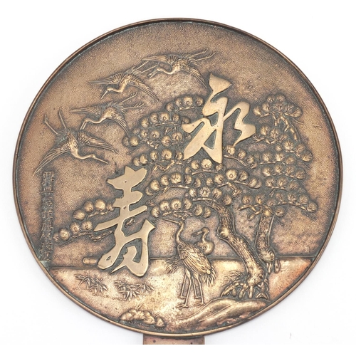 402 - Oriental polished bronze hand mirror cast with cranes and character marks, 34cm in length