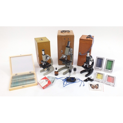 96 - Three microscopes together with a collection of prepared slides, all with cases