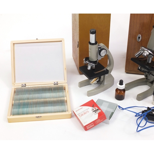 96 - Three microscopes together with a collection of prepared slides, all with cases