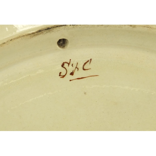 577 - Minton's pottery charger hand painted with two figures before a town, within a foliate border, impre... 