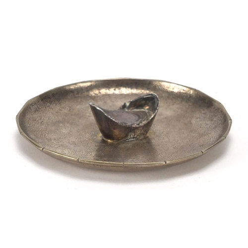 413 - Chinese silver ingot on a dish impressed NK and with character marks, 8.5cm in diameter, approximate... 