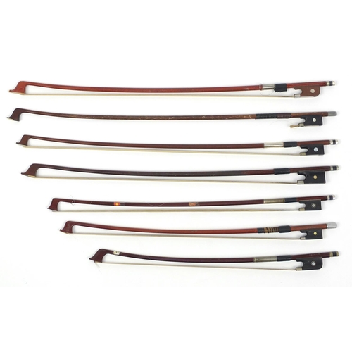144 - Seven wooden violin bows, some with Mother of Pearl frogs, the largest 58cm in length