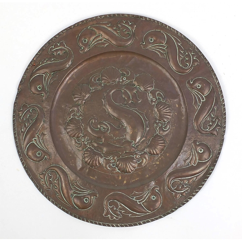 609 - Large Arts & Crafts copper charger embossed with stylised dolphins, 64cm in diameter