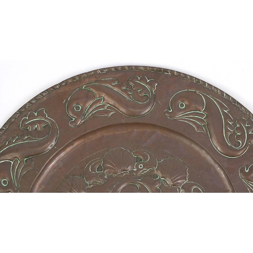 609 - Large Arts & Crafts copper charger embossed with stylised dolphins, 64cm in diameter